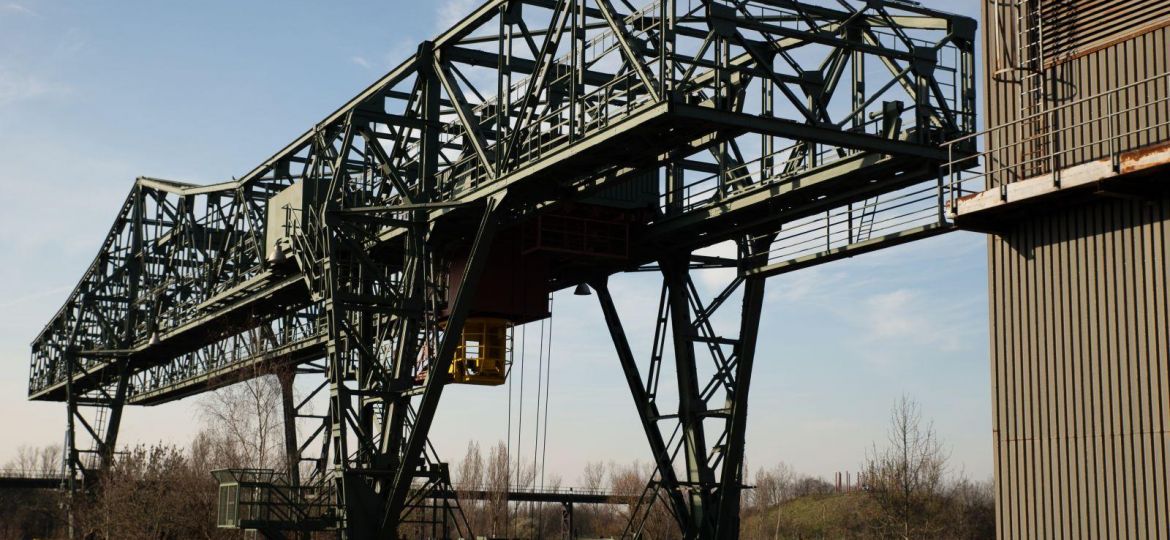 Wide shot of a huge metal structure and a building with a clear blue sky